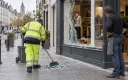 Agent municipal nettoyant devant une boutique endommagée